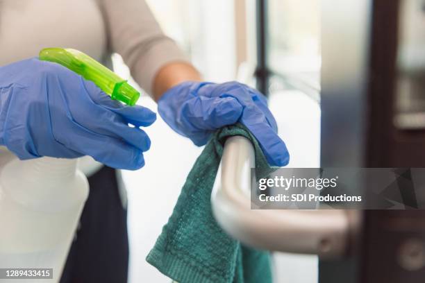 woman sanitizes handrail during covid-19 - covid 19 cleaning stock pictures, royalty-free photos & images