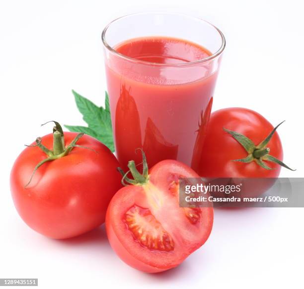 full glass of fresh tomato juice and tomatoes are round the galss,fawncreektownship,united states,kansas,usa - tomatensap stockfoto's en -beelden