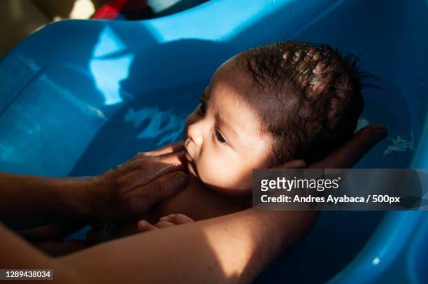 cropped hands of mother bathing son in bathtub with sunlight coming through window,cuenca,ecuador - ecuador family stock pictures, royalty-free photos & images