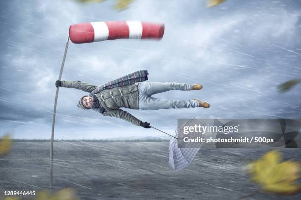 man getting blown away by a storm - 500px plus stockfoto's en -beelden