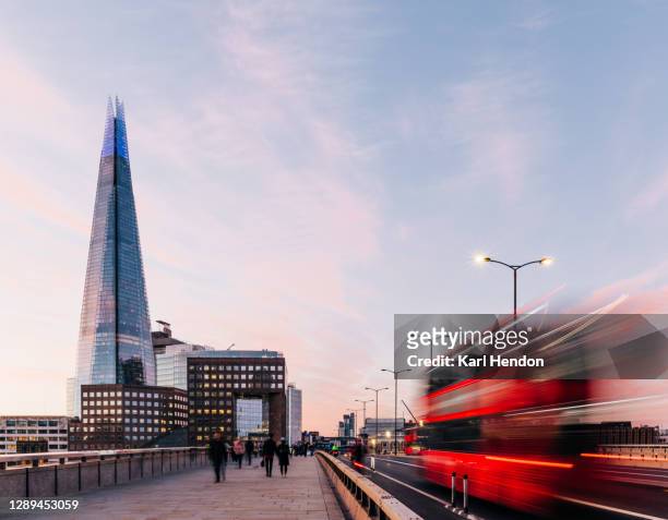a sunrise view of london bridge with blurred traffic and passer's by - london england stock-fotos und bilder