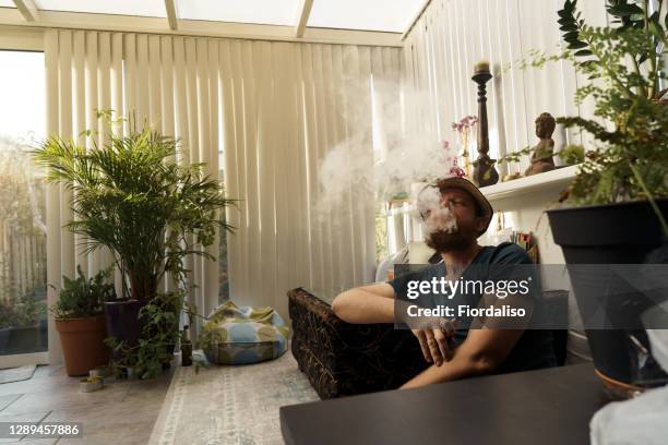 a man in a straw hat smoking through a veil of smoke - smoking weed stock-fotos und bilder