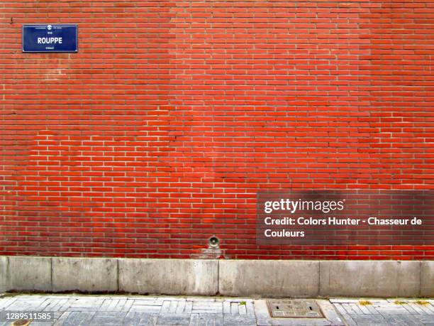 brussels street name plate on a weathered brick wall with sidewalk - straatnaambord stockfoto's en -beelden