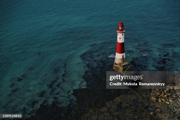 red and white lighthouse on the sea shore. - seven sisters uk stock pictures, royalty-free photos & images