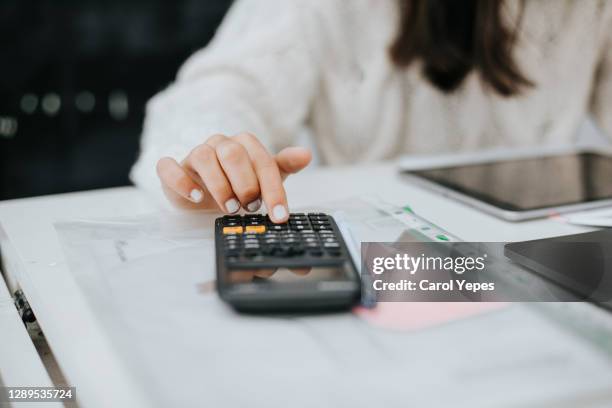 young woman preparing home budget, using laptop and calculator - orçamento imagens e fotografias de stock