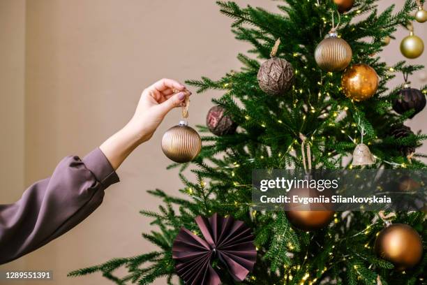 young woman's hand decorating christmas tree indoors. - decorare l'albero di natale foto e immagini stock
