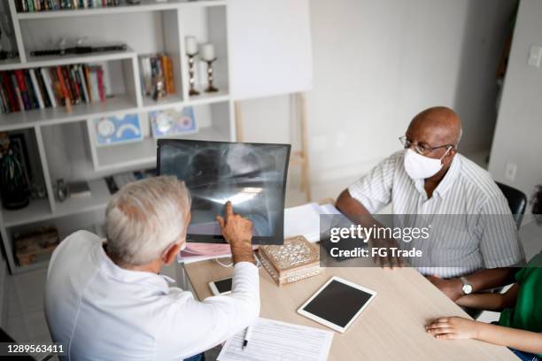 mature doctor showing x-ray to patient - using face mask - male chest stock pictures, royalty-free photos & images
