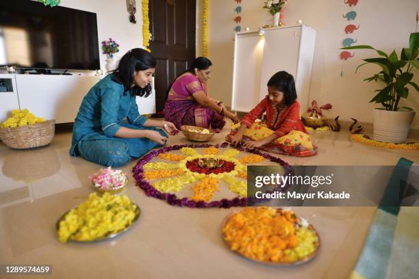 multi-generation indian family making floral rangoli for diwali celebration - rangoli stock pictures, royalty-free photos & images