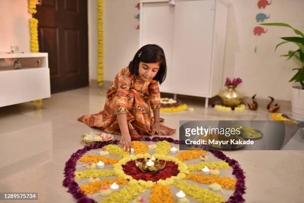 girl decorating floral rangoli with lamps for diwali celebration - rangoli stock pictures, royalty-free photos & images