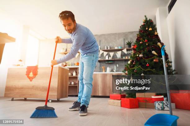 mid adult man barriendo piso con una escoba - barrer fotografías e imágenes de stock