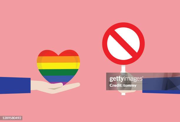 eine hand hält ein verbotsschild an ein regenbogenherz - vorurteil stock-grafiken, -clipart, -cartoons und -symbole
