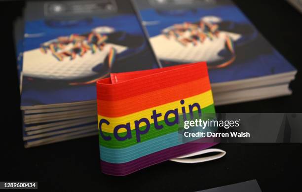 The rainbow coloured captain's armband is seen alongside the match day programme which features rainbow laces on the cover in support of the...