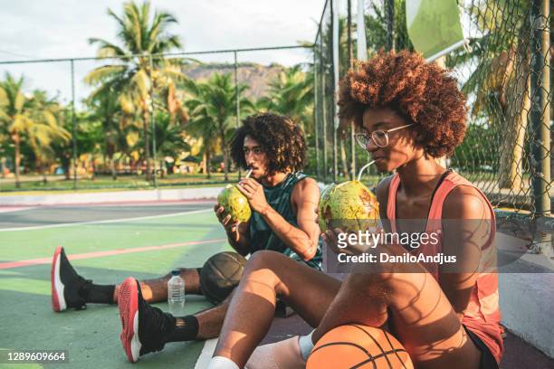 playful basketball players are relaxing at sports court - coconut water stock pictures, royalty-free photos & images
