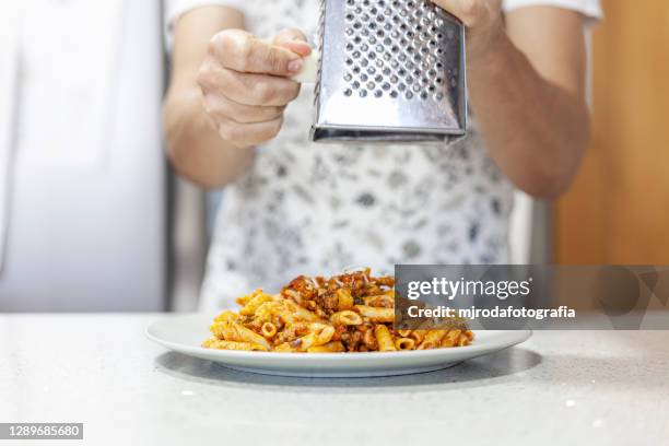 grating cheese on some macaroni - grattugia foto e immagini stock