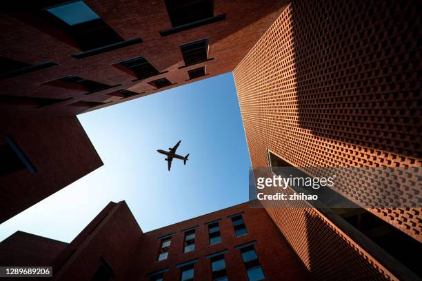 low angle view of airplane over brick building, illuminated by sunlight - low flying aircraft bildbanksfoton och bilder