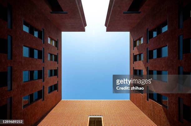 looking up at the symmetrical brick-concrete building directly above, exposed to the sun - building symmetry stock pictures, royalty-free photos & images