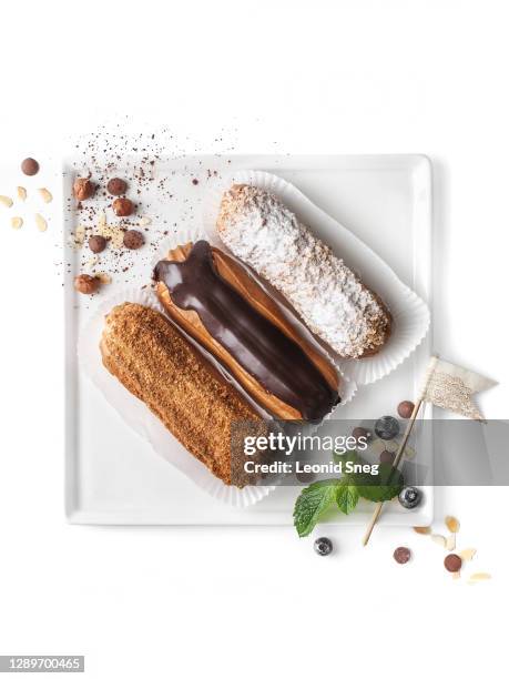 food photography of assorted eclair cakes with different fillings top view (chocolate, icing sugar, caramel) on a white background isolated close up - eclair stockfoto's en -beelden