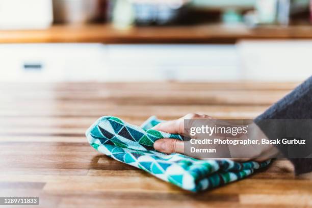 close-up of woman hand cleaning the surface of a table with a cleaning cloth at home - duster stock-fotos und bilder