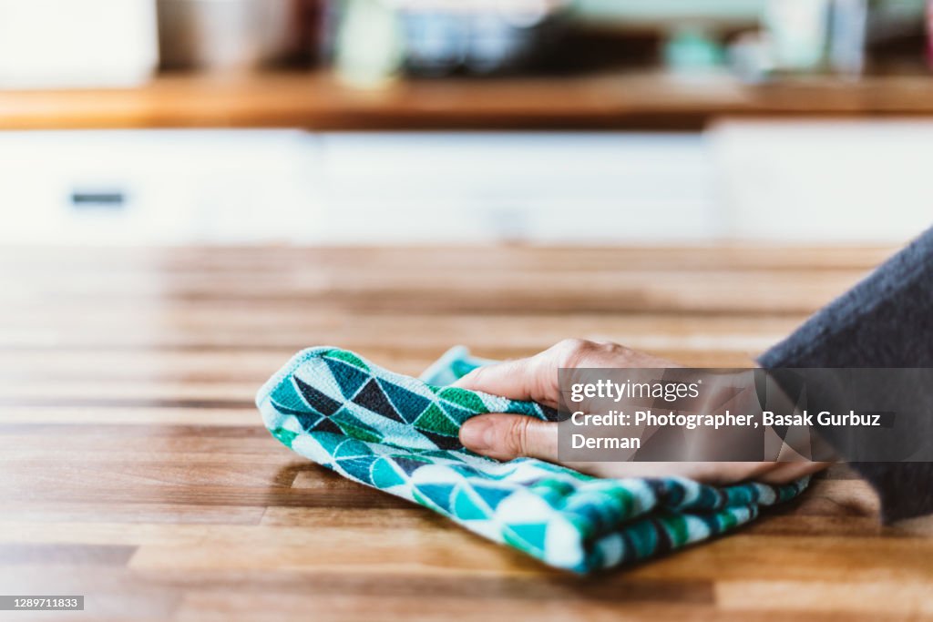 Close-up of woman hand cleaning the surface of a table with a cleaning cloth at home