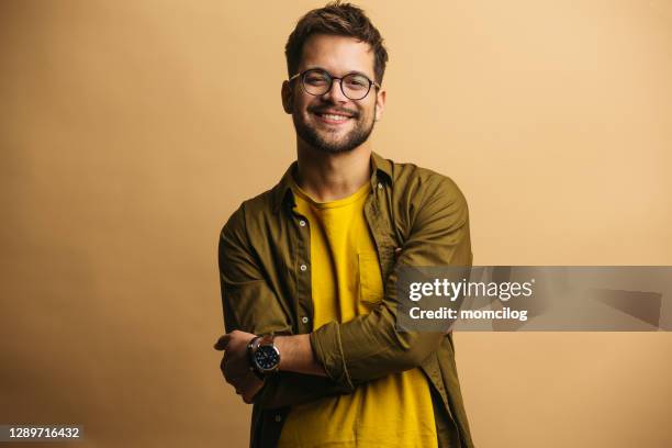 jovem adulto confiante masculino em pé e sorrindo - braços cruzados - fotografias e filmes do acervo