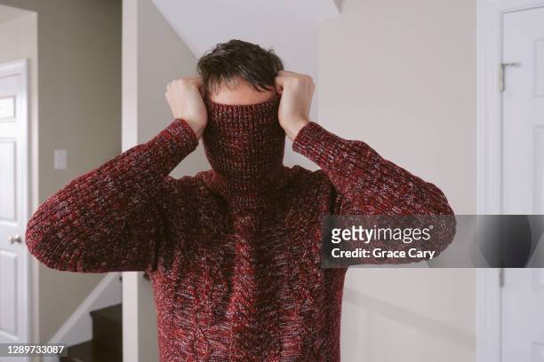 man covers face with sweater - maglione foto e immagini stock