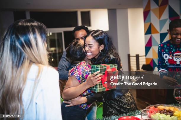 woman embracing friend during christmas party - the party arrivals stock-fotos und bilder