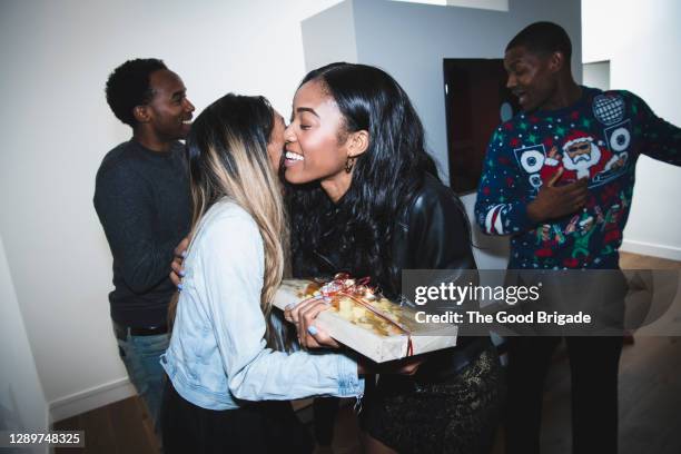 smiling woman welcoming friends at christmas party - african american christmas images stock-fotos und bilder