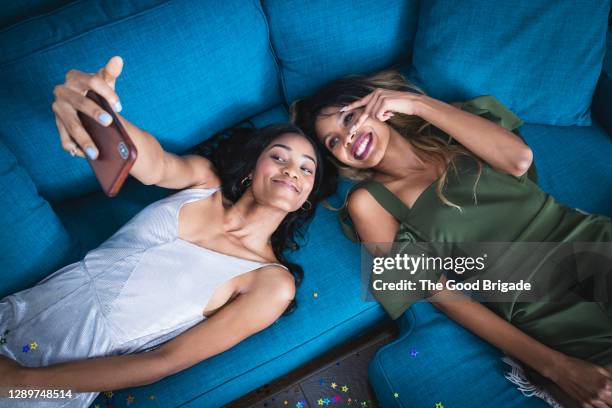 directly above shot of young woman taking selfie while lying on sofa - blue sofa stock pictures, royalty-free photos & images