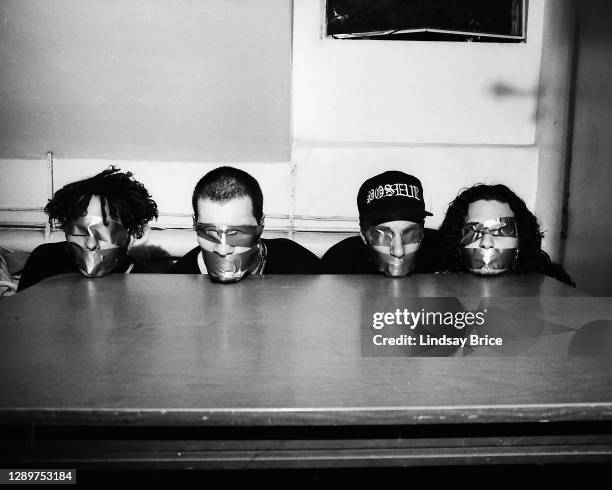 Zack de la Rocha, Tim Commerford, Tom Morello, and Brad Wilk are posed as hostages, blindfolded and gagged with duct tape, their heads in a line upon...