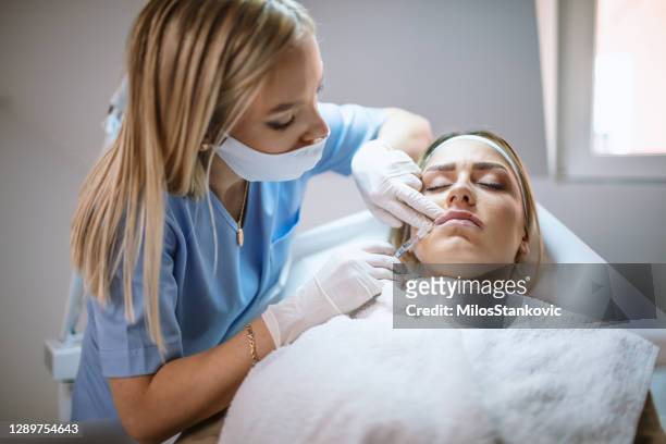 lip augmentation procedure of a beautiful woman in a medical clinic. - lip injections stock pictures, royalty-free photos & images