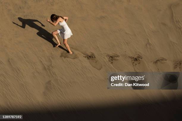 Girl runs through the sand dunes at sunset on December 05, 2020 in Maspalomas, Spain. The dunes at Maspalomas have seen a positive transformation...