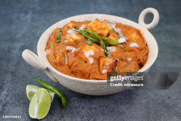 image of kadhai-style serving bowl filled with homemade shahi paneer (cheese curry), thick gravy, cream, tomatoes, indian spices, grey background, focus on foreground - masala stock pictures, royalty-free photos & images