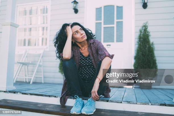 sad woman sitting alone in front of her porch - irrational fear stock pictures, royalty-free photos & images