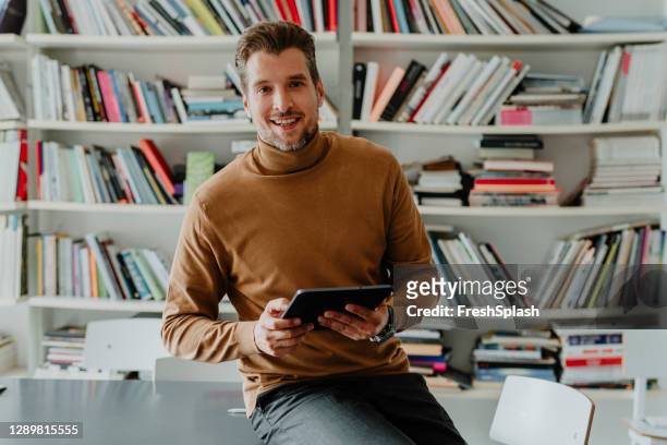 porträt eines lächelnden freiberuflichen geschäftsmannes mit einem digitalen tablet in seinem büro/bibliothek - sweatshirt stock-fotos und bilder