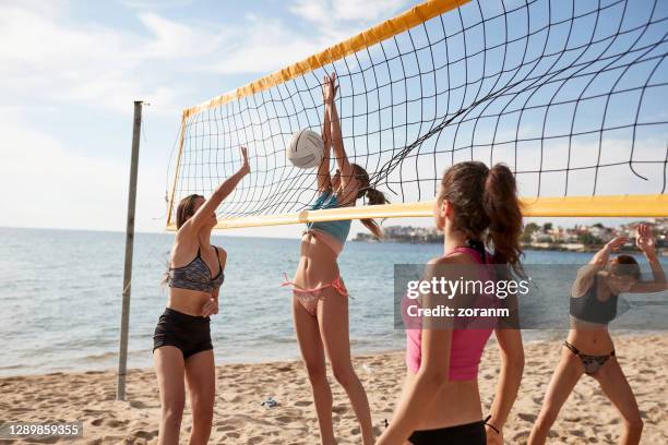young women in bikinis playing beach volley, lost point, ball in net - beach volleyball spike stock pictures, royalty-free photos & images