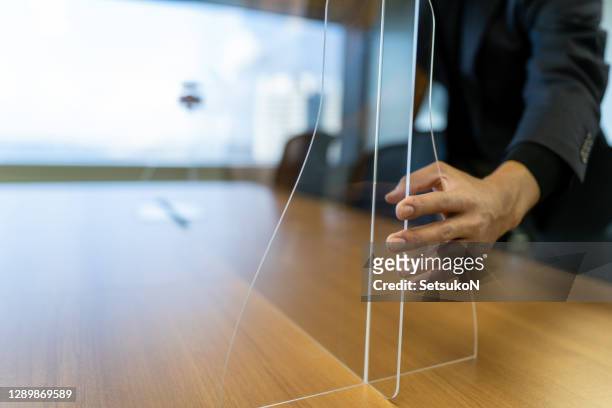 aziatische zakenman die acrylglas op het bureau bevestigt - perspex stockfoto's en -beelden