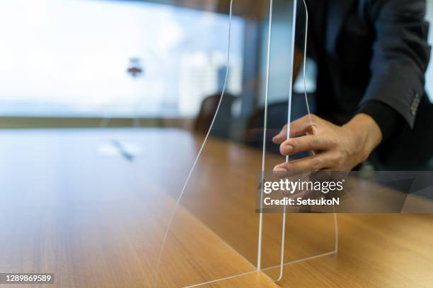 empresário asiático fixando vidro acrílico na mesa - perspex - fotografias e filmes do acervo