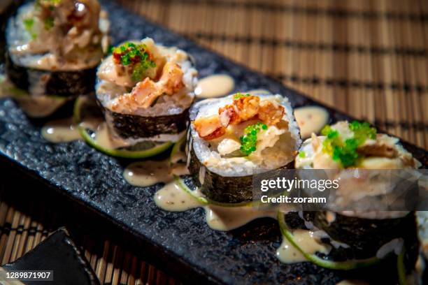 nahaufnahme von sushi-rollen in nori auf rechteckigem sushi-teller aufgereiht - miso stock-fotos und bilder