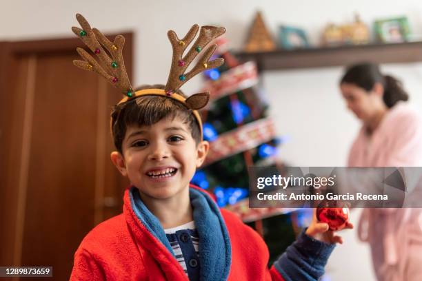 boy helps his mother to decorate the christmas tree on a cold winter morning, he si happy looking at camera - headband stock pictures, royalty-free photos & images
