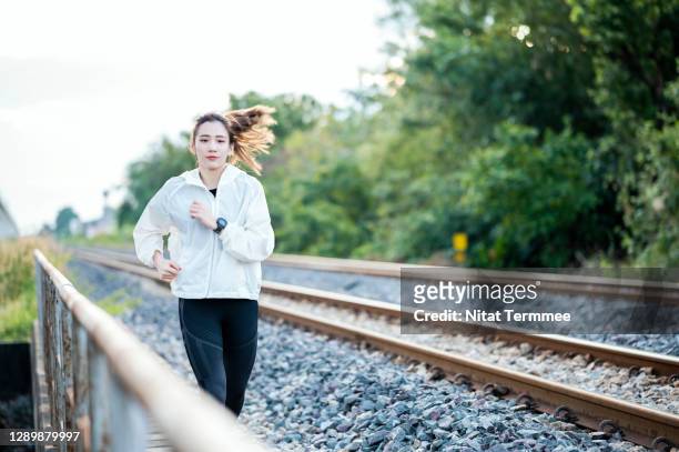 healthy asian female runner jogging in next to outside city railway. healthy, active lifestyle concepts. - asian female bodybuilder stock pictures, royalty-free photos & images