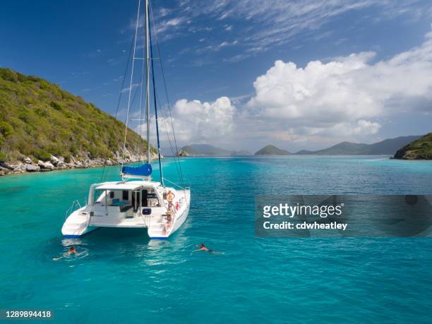 catamarán anclado con peope relajante por lovango cay, islas vírgenes - catamaran fotografías e imágenes de stock