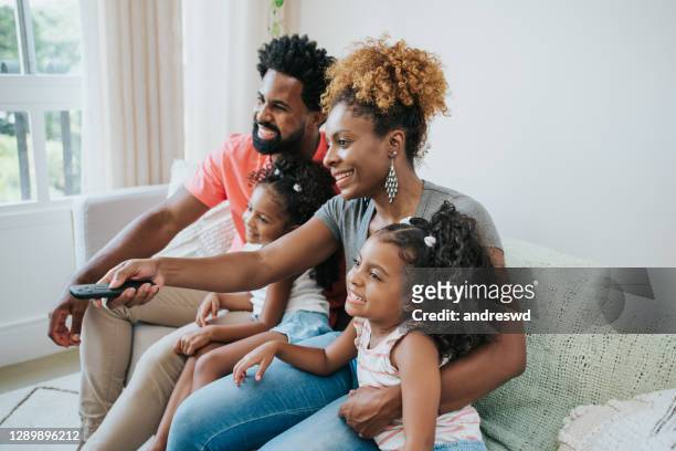 familie die tv op bank in huis woonkamer bekijkt gebruikend afstandsbediening - african family watching tv stockfoto's en -beelden