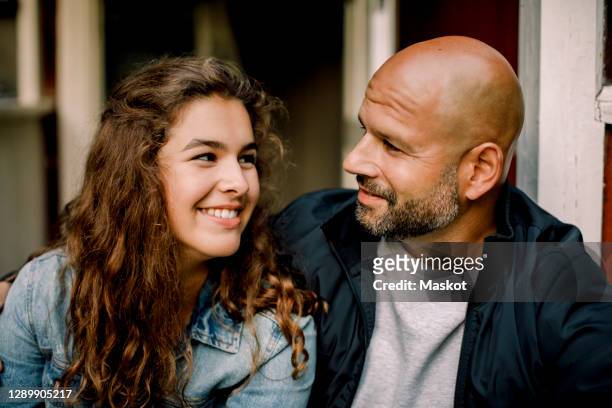 smiling teenager looking at father while talking outdoors - daughter stock-fotos und bilder