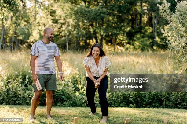 cheerful woman with male partner playing molkky in yard - bend over woman stock pictures, royalty-free photos & images