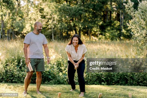 cheerful woman with male partner playing molkky in yard - woman bending over imagens e fotografias de stock