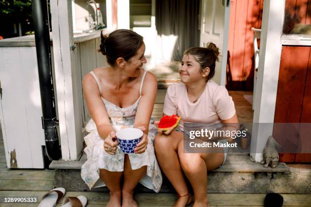 cheerful mother talking to daughter eating slice of watermelon outdoors - gourd bildbanksfoton och bilder