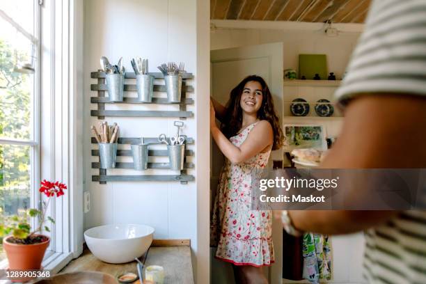 smiling daughter talking to father while standing by closet at home - speisekammer stock-fotos und bilder
