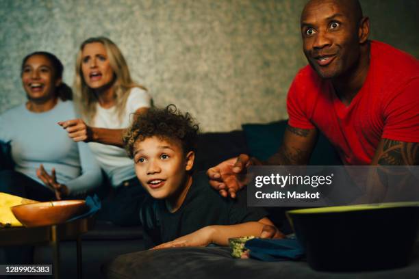 excited sports fans watching tv together at night - family tv stock-fotos und bilder