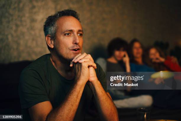 hopeful man praying while watching sports at night - family game night stock pictures, royalty-free photos & images