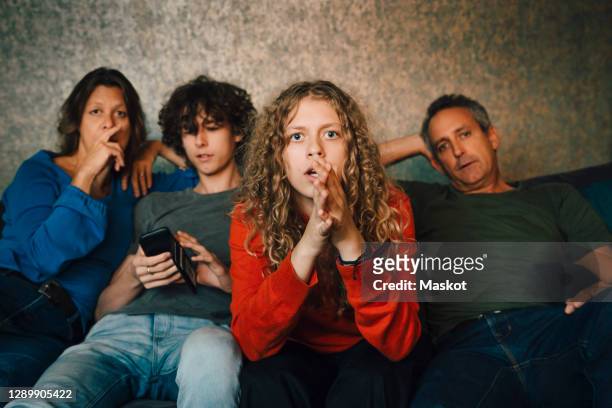 girl praying while watching sports with family at home - family game night stock pictures, royalty-free photos & images